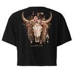 Black short-sleeve crop top t-shirt showing the back graphic, which features a decorated animal skull with curved horns, a floral crown, and dangling tassels. The text 'WILDFLOWER PRINCE' is printed below the graphic.