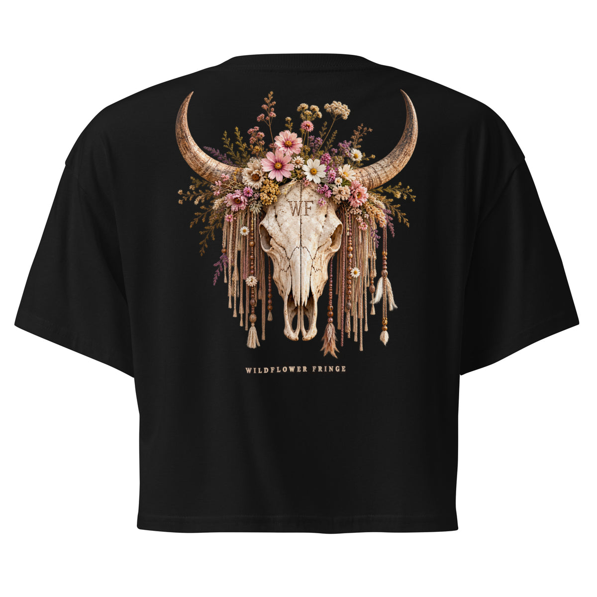 Black short-sleeve crop top t-shirt showing the back graphic, which features a decorated animal skull with curved horns, a floral crown, and dangling tassels. The text 'WILDFLOWER PRINCE' is printed below the graphic.