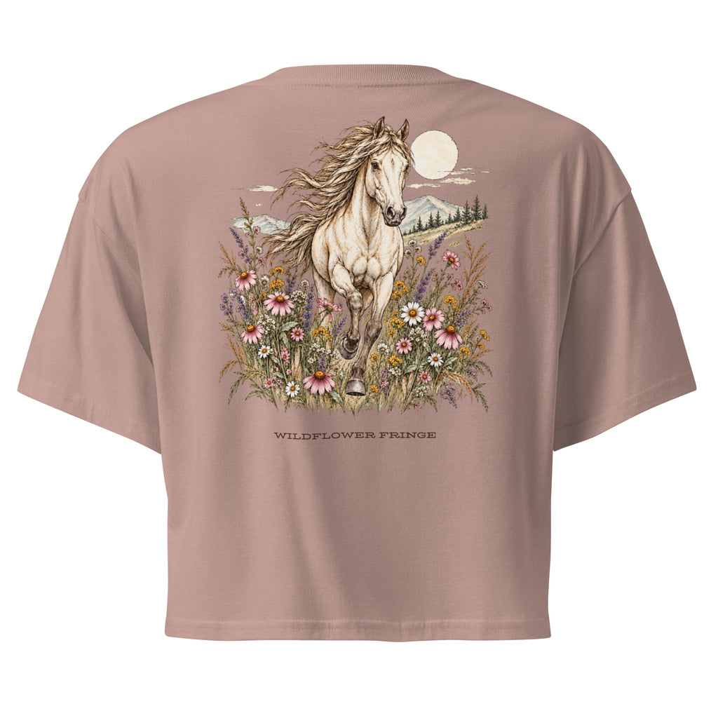 A dusty rose short-sleeve t-shirt shown from the back, featuring a large graphic print of a white horse running through wildflowers under a full moon, with the text 'WILDFLOWER PRINCE' printed below.