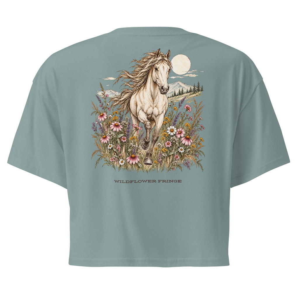 A sage green short-sleeve t-shirt shown from the back, featuring a large graphic print of a white horse running through wildflowers under a full moon, with the text 'WILDFLOWER FRINSE' printed below.