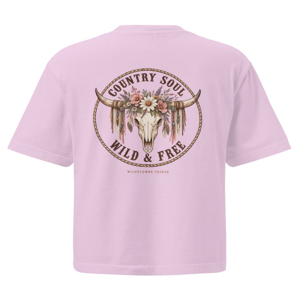 A light pink short-sleeve t-shirt shown from the back, featuring a large circular graphic with a steer skull, floral crown, and the words 'COUNTRY SOUL WILD & FREE' in brown.