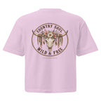 A light pink short-sleeve t-shirt shown from the back, featuring a large circular graphic with a steer skull, floral crown, and the words 'COUNTRY SOUL WILD & FREE' in brown.